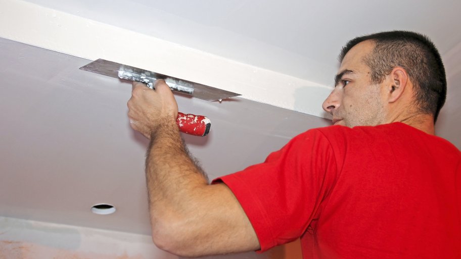 Contractor in red shirt skimming a ceiling